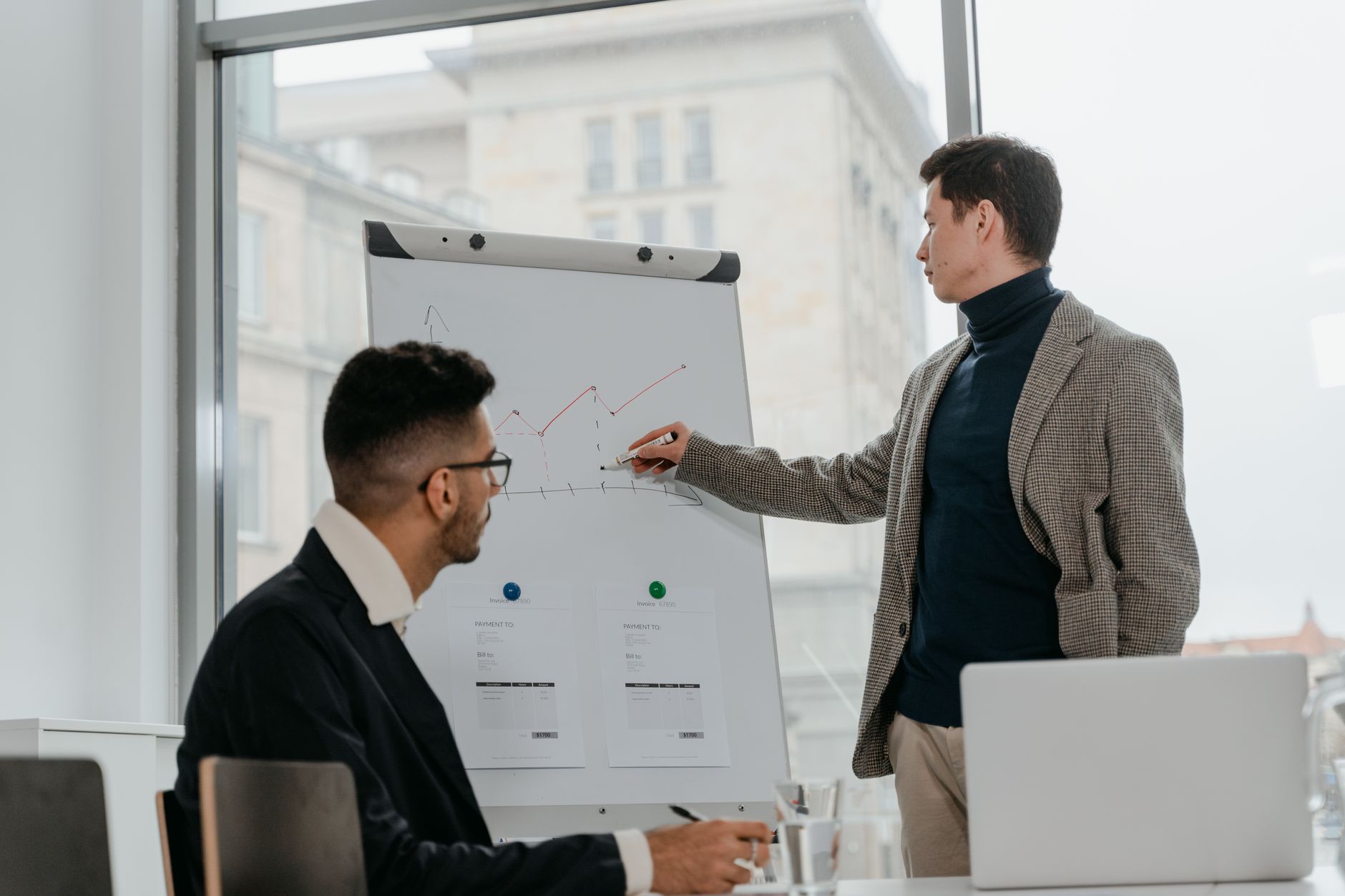 Two businessmen discussing data on a flipchart in a contemporary office setting. — From Beginner to Expert: White Label Faceb