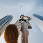 Low-angle shot of a man in a suit framed by skyscrapers and a passing airplane. — The Advantages of Proprietary Trading for P