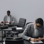 Business office with diverse employees in gray suits working at desks in an indoor setting. — The Value of Locksmith Services