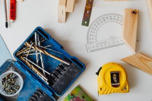A selection of carpentry tools including drill bits, measuring tape, and protractor in an overhead shot. — What Should I Look